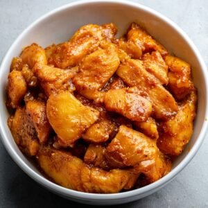 A bowl of marinated chicken pieces, coated in a flavorful mixture, ready to be cooked.