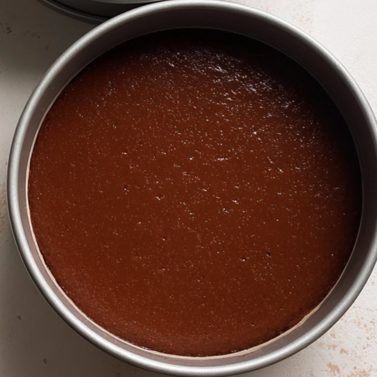 The second image depicts the cake batter before being baked, perfectly even in two pans.