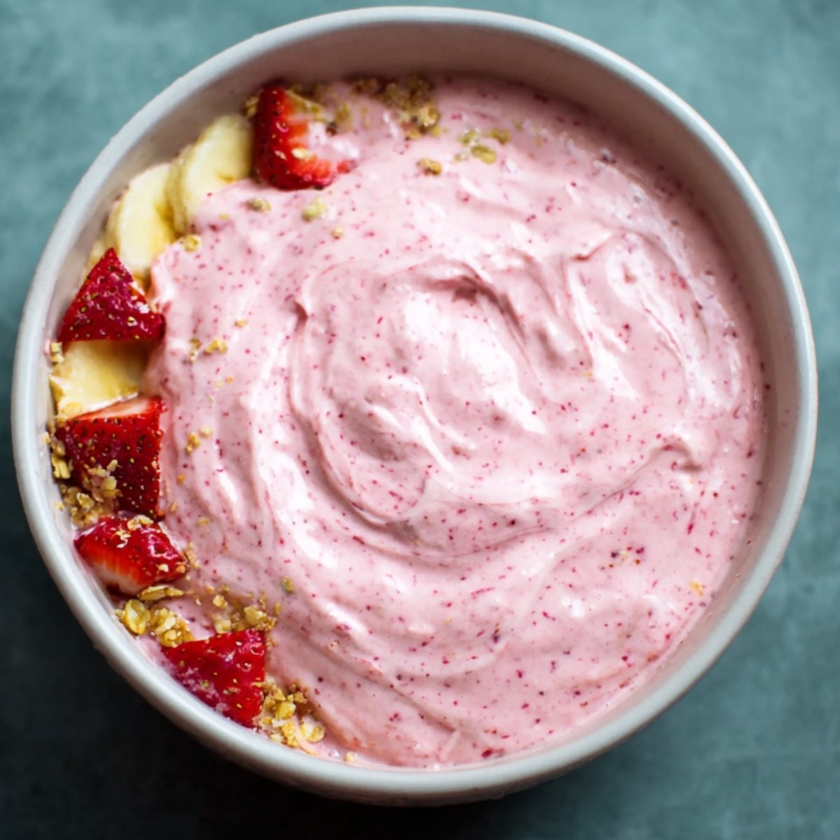 A creamy, pink smoothie or yogurt bowl with a smooth texture, likely topped with fruit.