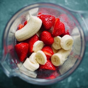 A blender filled with chopped bananas and strawberries, ready to be blended into a smoothie.