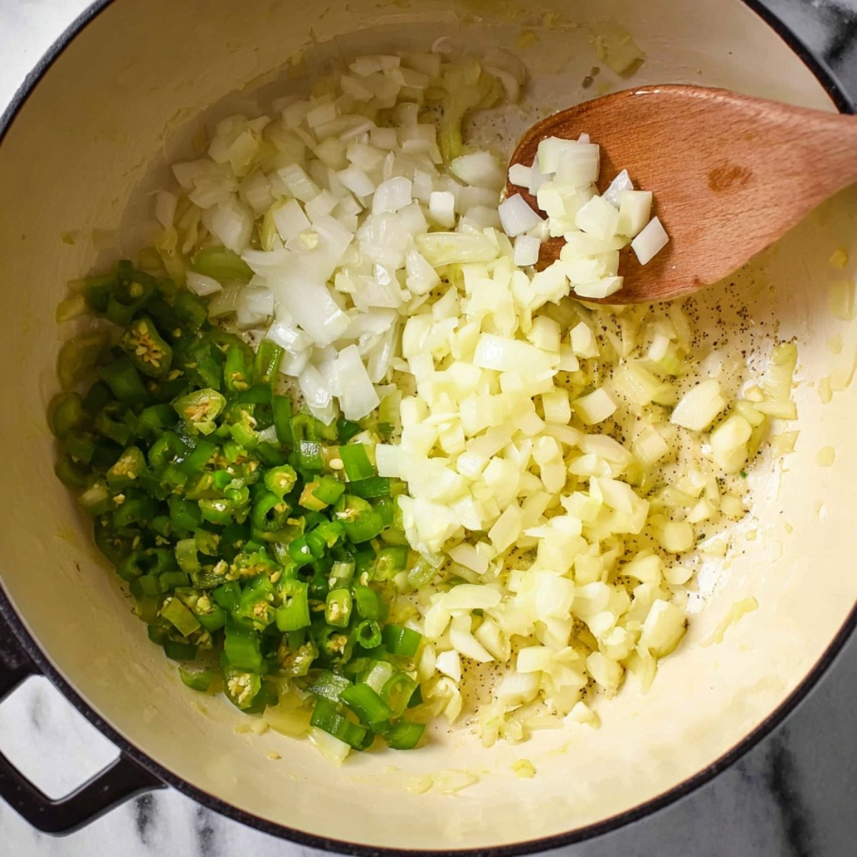 A pot with diced onions, garlic, and green chilies being sautéed together, filling the air with aromatic flavors