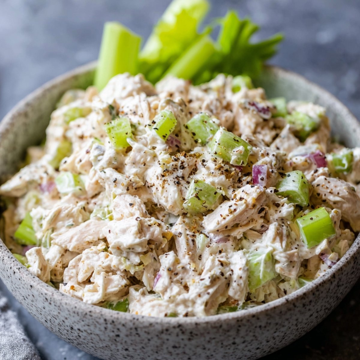 Chicken Salad A fresh serving of chicken salad in a bowl, garnished with black pepper and celery pieces, perfect for a light meal or sandwich filling
