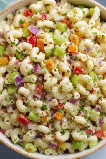 Macaroni Salad A vibrant overhead view of a delicious macaroni salad filled with colorful diced vegetables, perfectly mixed and ready to serve in a large bowl.