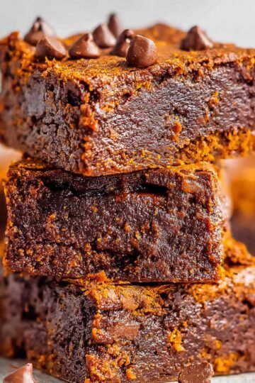 Sweet Potato Brownies A stack of perfectly baked sweet potato brownies, showcasing their rich, fudgy texture and dotted with chocolate chips for a decadent treat.