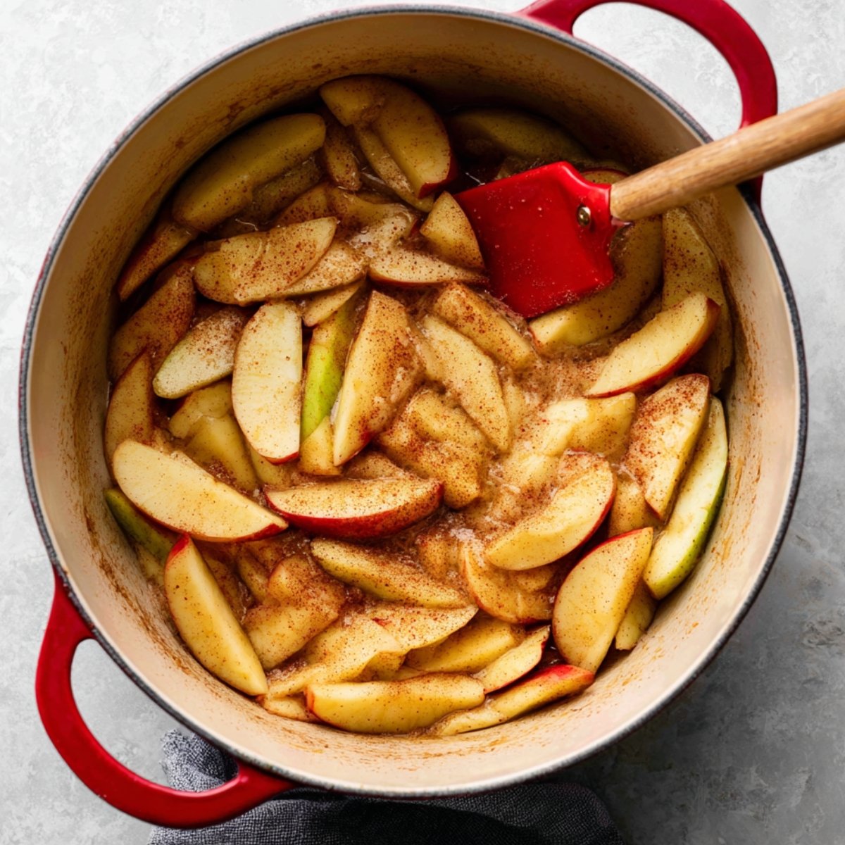 Apple pie filling made of soft, cinnamon-spiced apples, neatly arranged in a pie crust, awaiting the final topping for an oven bake