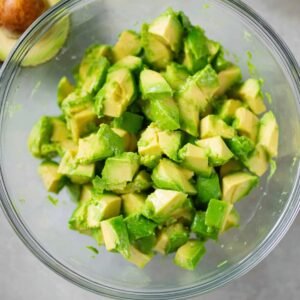 A close-up view of diced avocado in a clear bowl, with the vibrant green pieces showing the creamy texture, ready to be mixed into a salad
