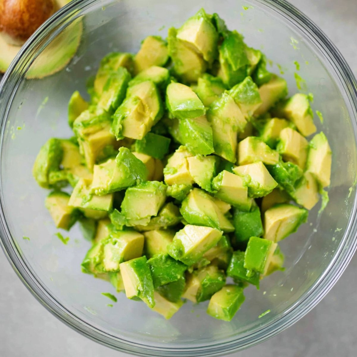 A close-up view of diced avocado in a clear bowl, with the vibrant green pieces showing the creamy texture, ready to be mixed into a salad