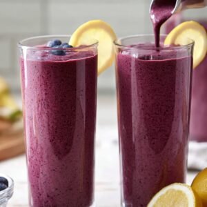 "Prepare a healthy and vibrant blueberry-banana smoothie that blends antioxidant-rich blueberries with the creamy texture of bananas. Add a splash of lemon for a zesty, refreshing kick. The resulting smoothie should have a smooth, velvety consistency, poured into tall glasses, and garnished with fresh blueberries and a slice of lemon. It's the perfect drink to kickstart your morning or enjoy as a nutritious snack!"