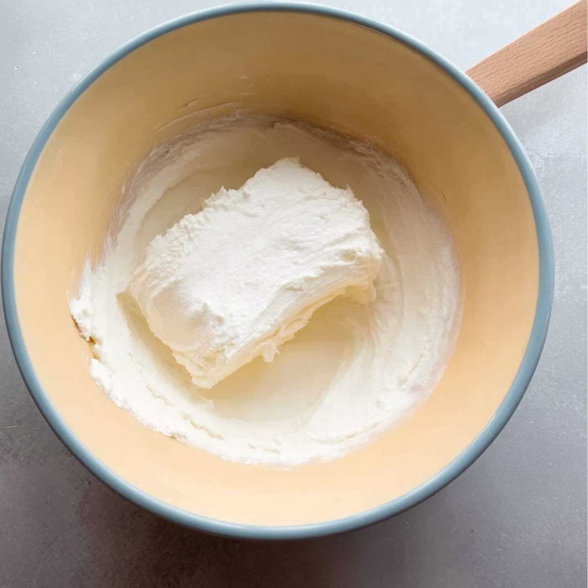 "Start by preparing the creamy filling for your cheese danish. Combine softened cream cheese with a pinch of sugar in a bowl, mixing until smooth and well-combined. This filling will form the rich, decadent center of the danish. Make sure the cream cheese is softened to ensure a smooth and creamy texture when mixed."