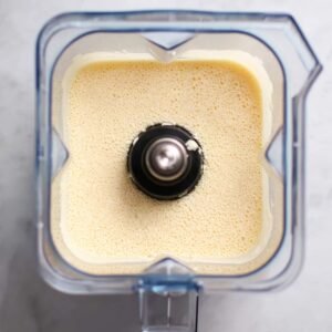 A blender filled with the smooth and creamy batter for a Dutch Baby pancake, showcasing the mixture of eggs, milk, flour, sugar, salt, and vanilla extract before baking.