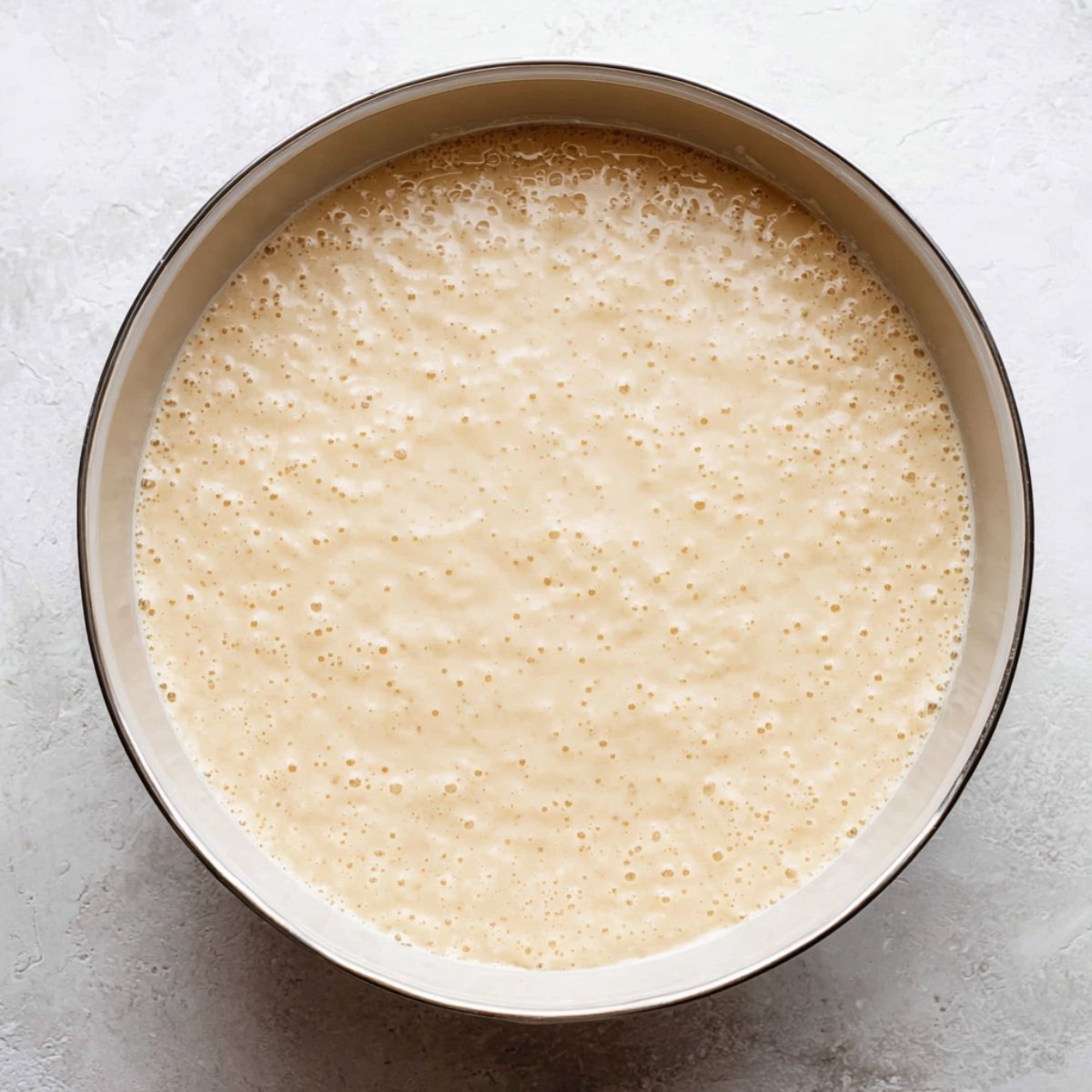 A close-up shot of muffin batter in a bowl, showing a smooth and bubbly texture, likely prepped and ready for baking.