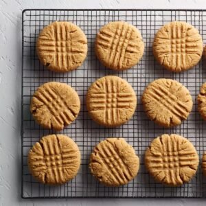 Peanut butter cookies with crisscross fork marks cooling on a black wire rack, photographed from above.