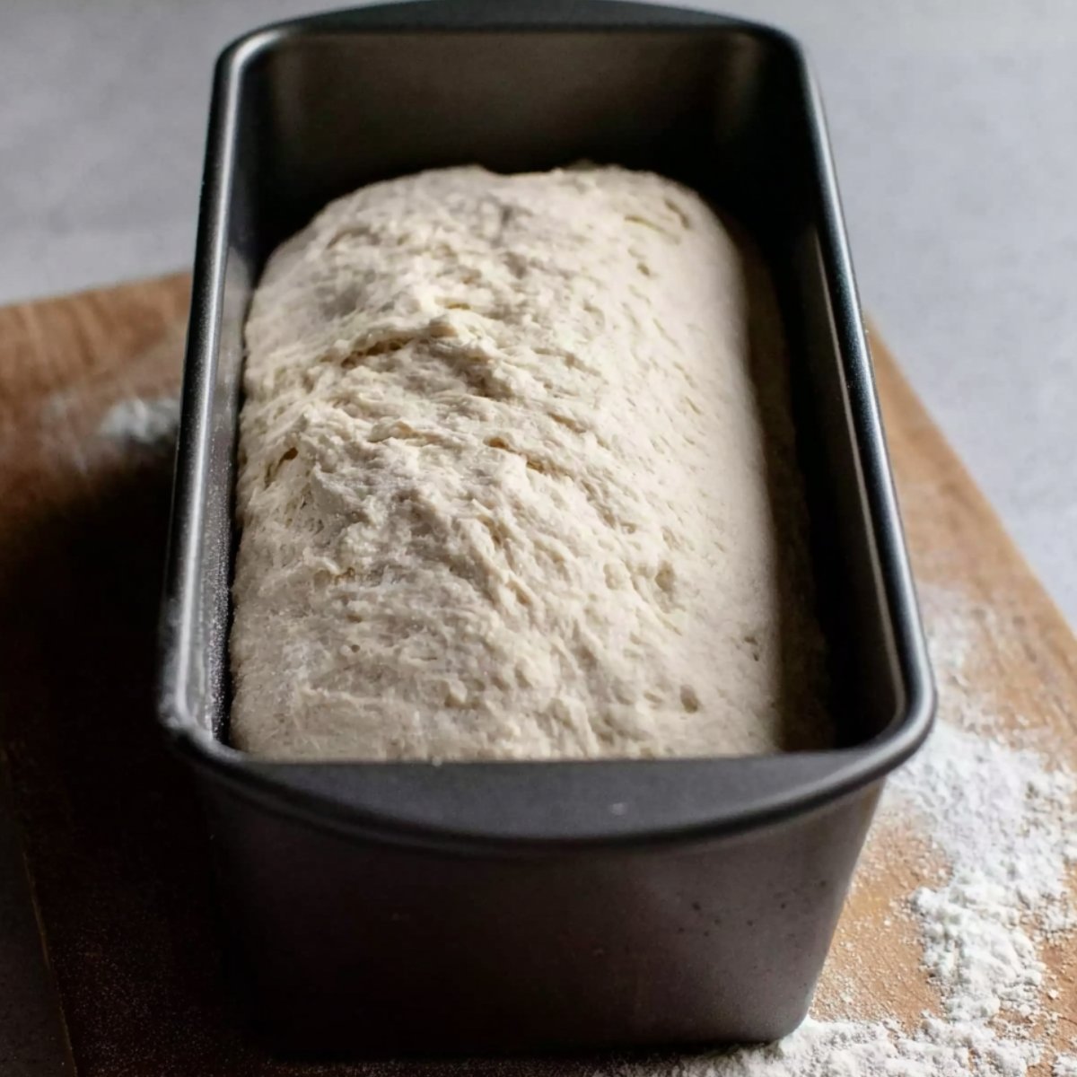 "Bread dough rises in a loaf pan, expanding as it prepares to be baked."