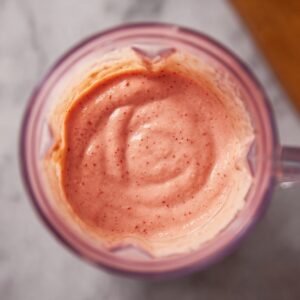 A close-up shot of a creamy, blended strawberry mango smoothie in a blender, showing its smooth and rich texture.