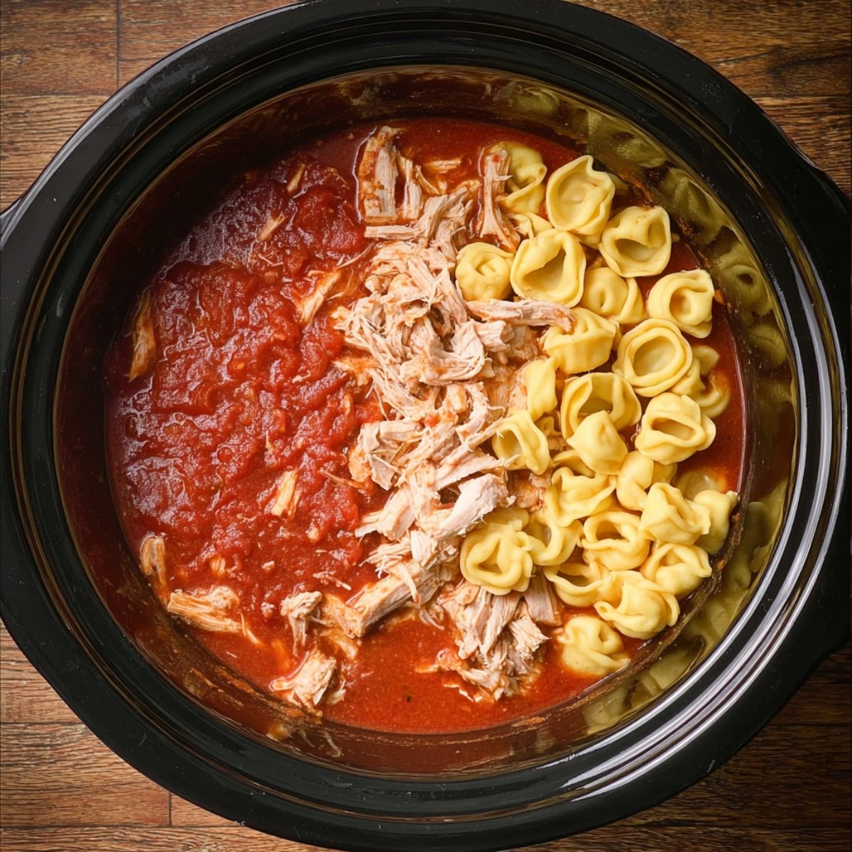 A delicious bowl of tortellini pasta topped with a creamy tomato sauce, shredded chicken, fresh basil, and a sprinkle of grated Parmesan cheese.