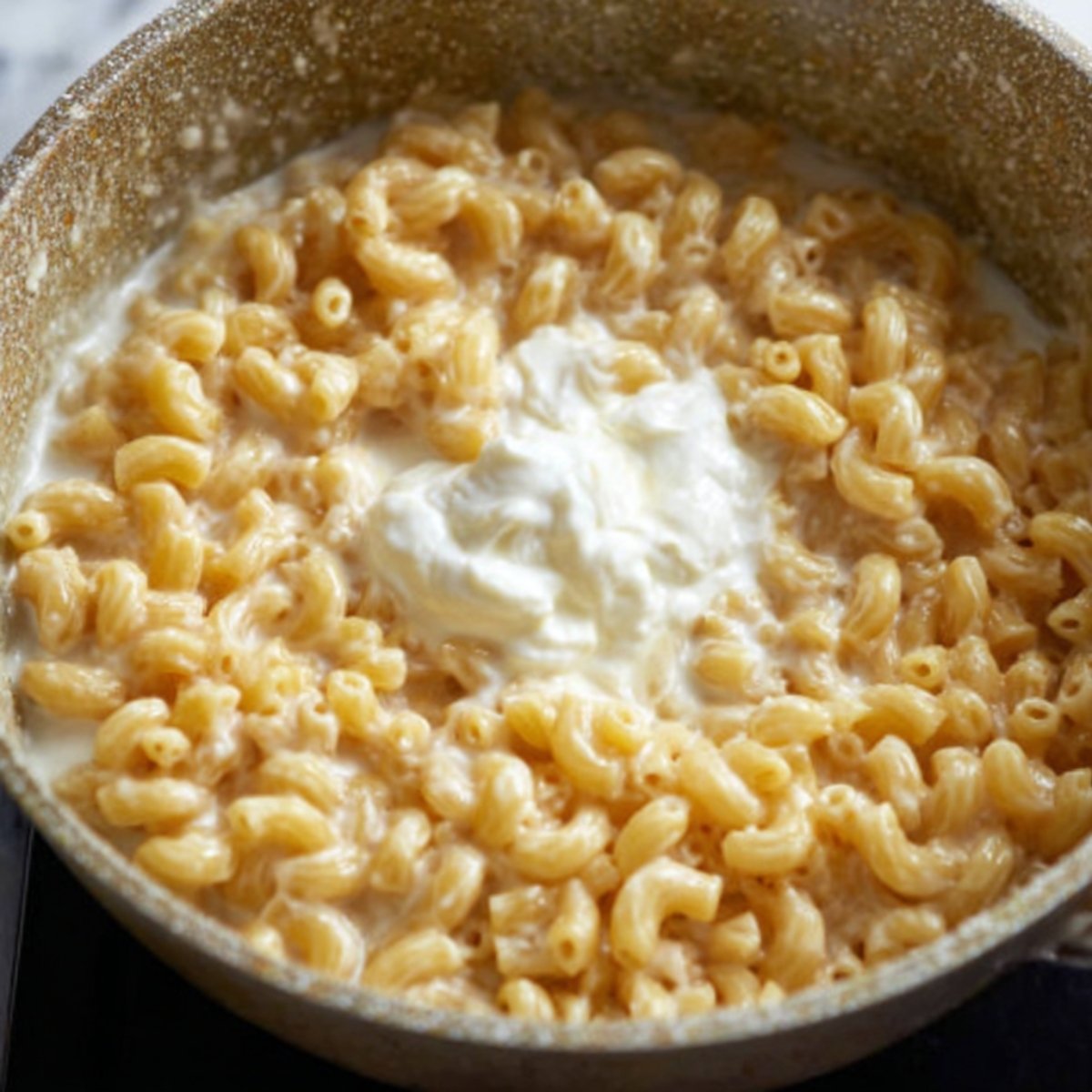 Top-down view of a saucepan with ingredients for cheese sauce, including butter, milk, cream, shredded cheese, salt, and black pepper, not yet mixed, ready for cooking, bright natural lighting.