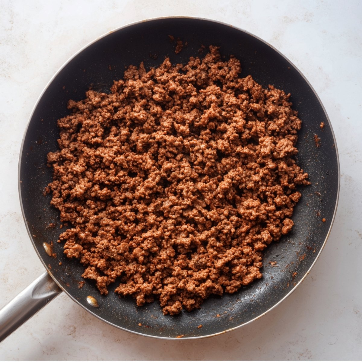 Cooked ground beef browned in a nonstick skillet, evenly crumbled