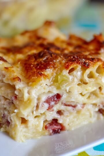 A close-up of cooked Corned Beef and Cabbage Casserole draining in a white colander, showing their soft, slightly curly texture.