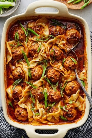 Baked meatballs and Dumpling Bakein a creamy sauce, garnished with chopped green onions, served in a white rectangular baking dish