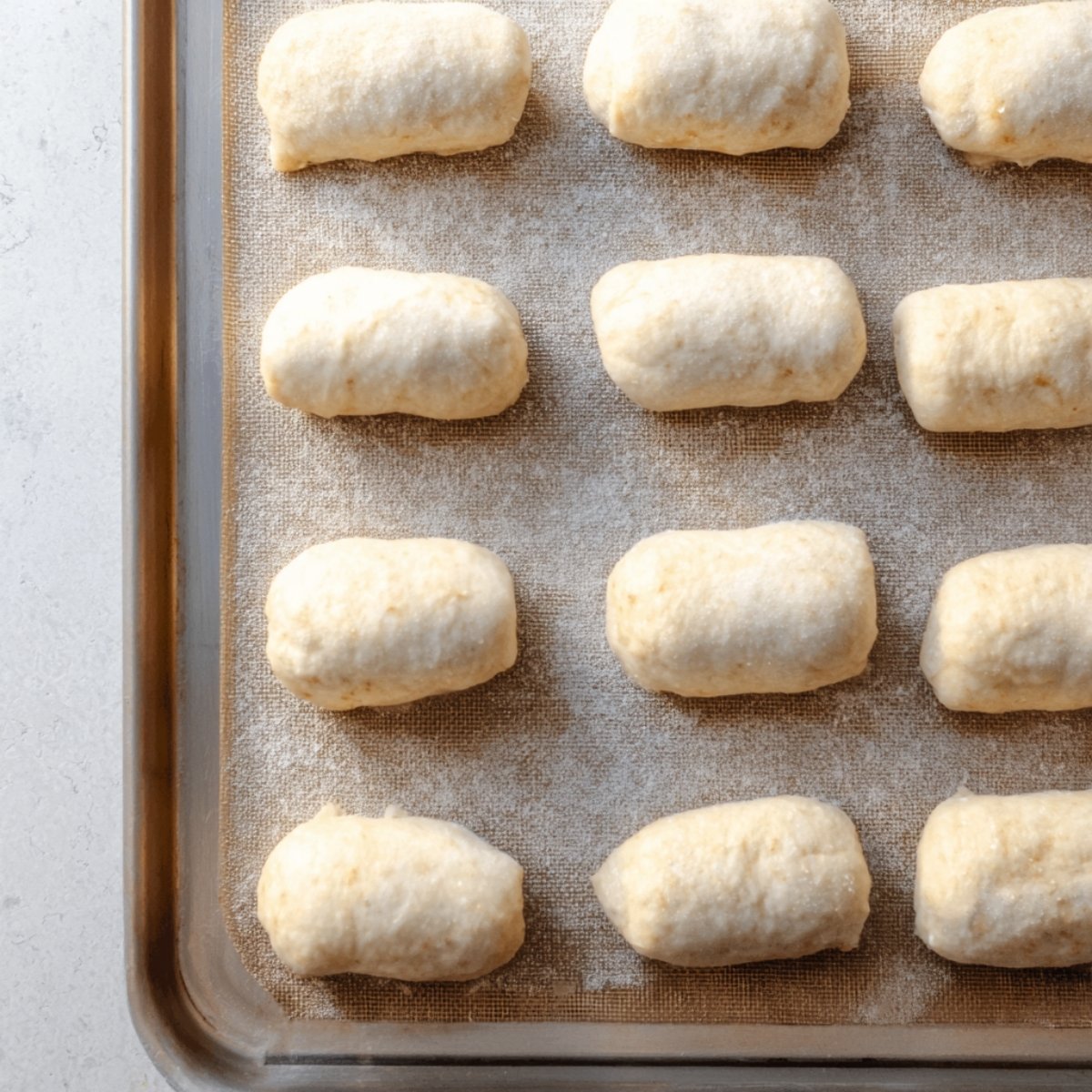 Unbaked rolled dough pieces filled and placed neatly on a baking sheet, ready to bake