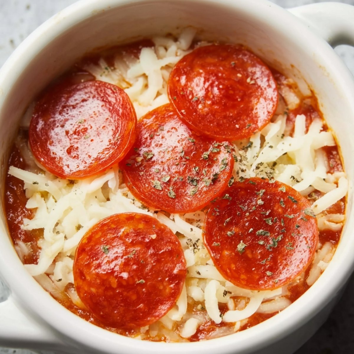 Overhead view of a white bowl with a mixture of tomato sauce, ricotta cheese, and dried Italian herbs, ready to be stirred.