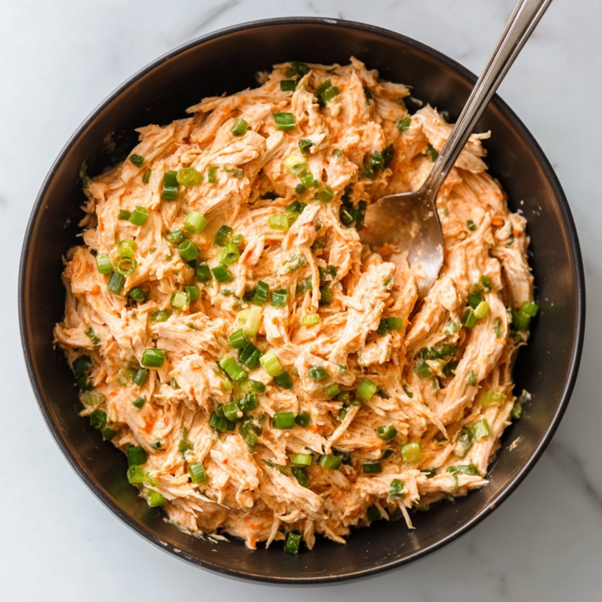 Layered sushi bake with rice, diced avocado, and cooked shrimp, topped with black and white sesame seeds and shredded nori