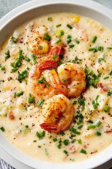 Bowl of creamy seafood bisque topped with cooked shrimp and chopped chives