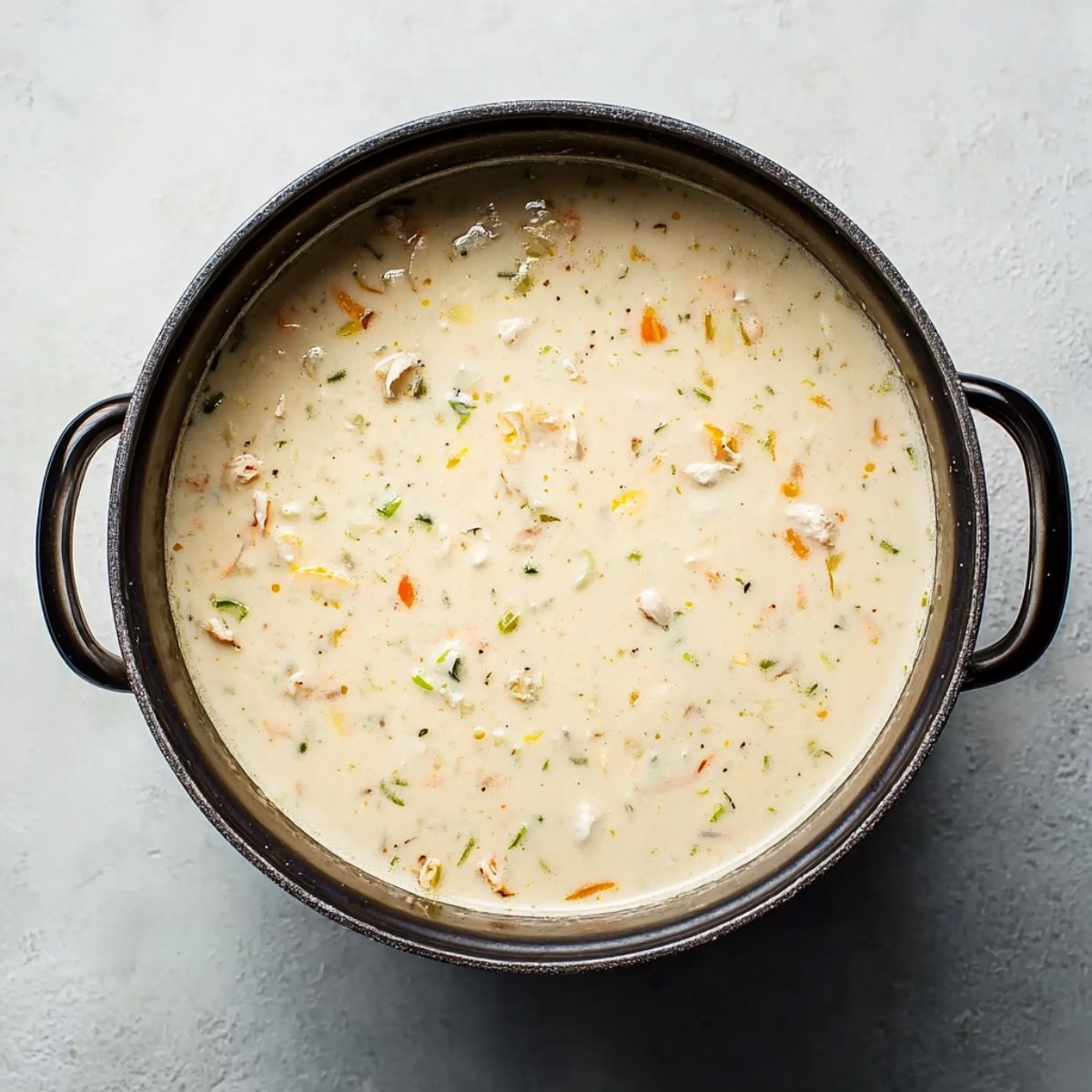 Large pot of creamy seafood bisque with visible chunks of vegetables and seafood