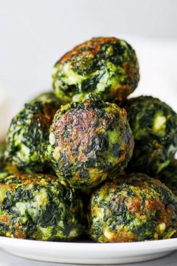 Cooked and golden-brown Spinach Balls and cheese balls stacked in a white bowl, showing crispy edges and a tender interior.